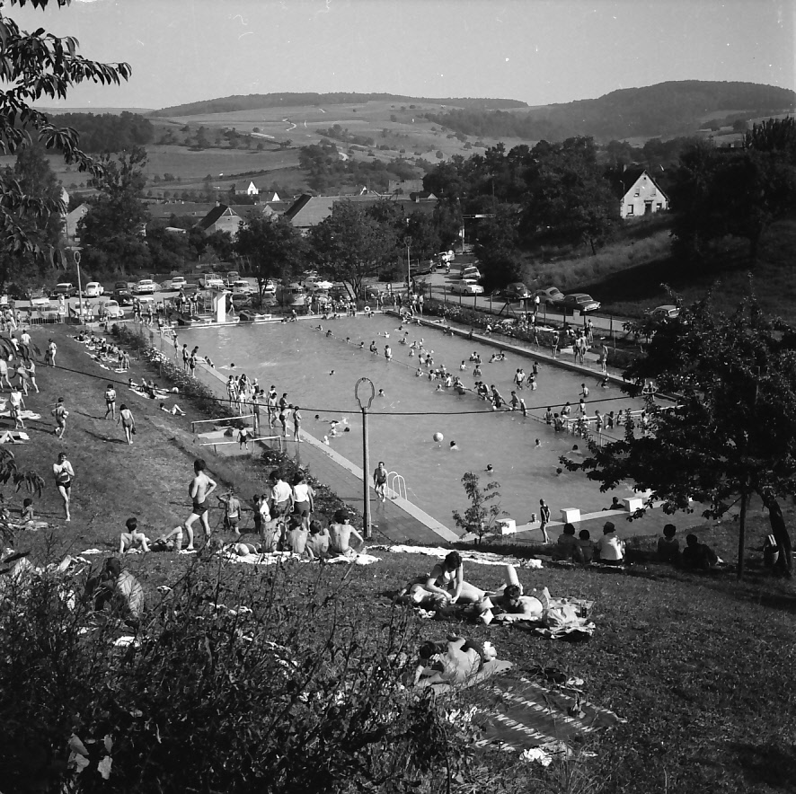 alte Schwarz-weißaufnahme des Schwimmbades mit Badegästen auf der Liegewiese und im Wasser